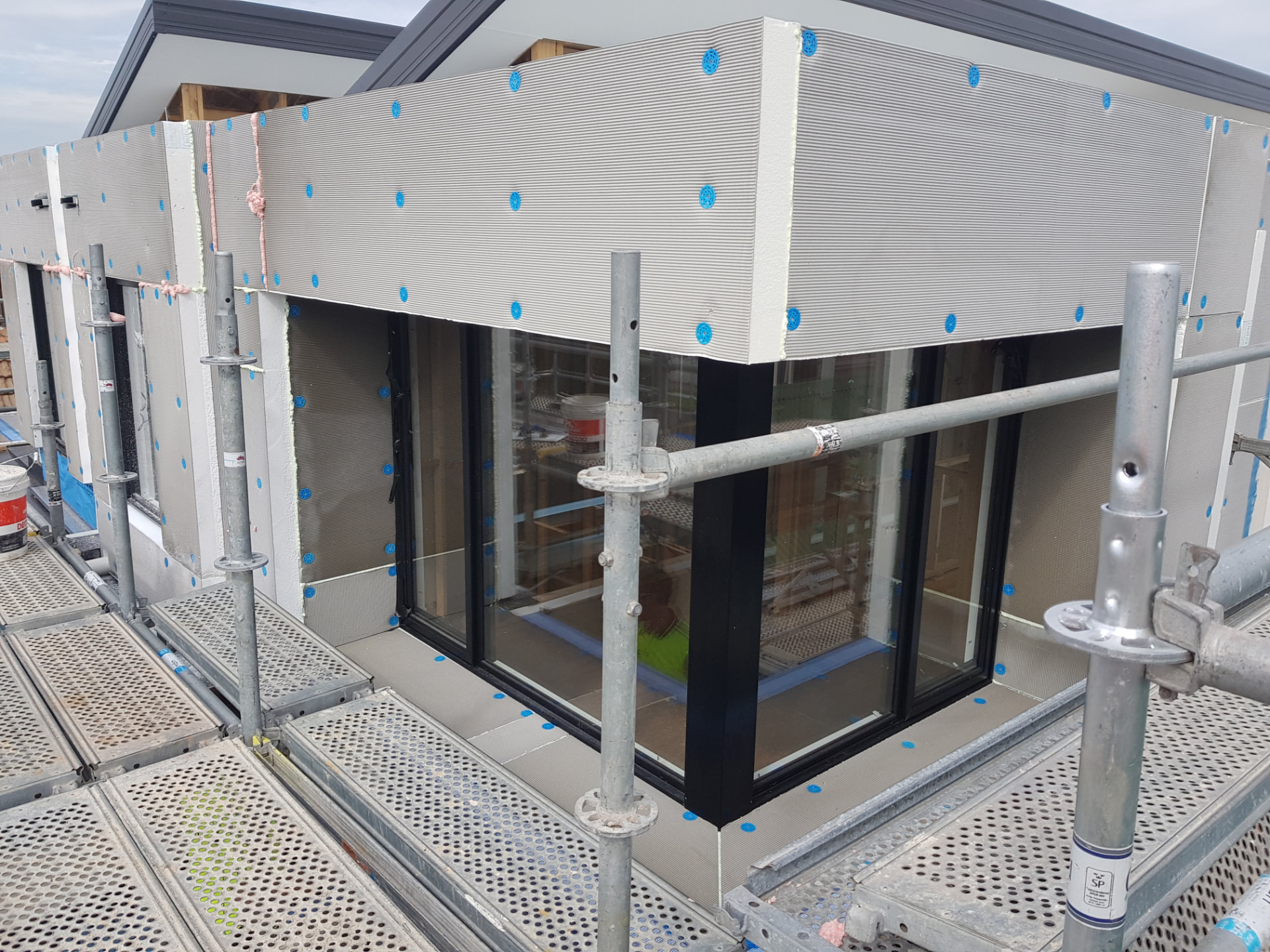Hebel PowerPanel lightweight cladding on a townhouse facade, mid-installation with scaffolding and blue fixings visible